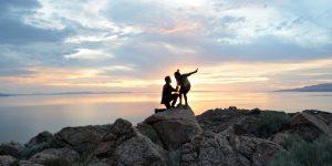 Silhouette of man one knee proposing to woman with ocean background