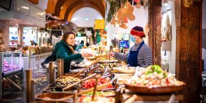 Vendor wearing a mask is selling fruit to a woman