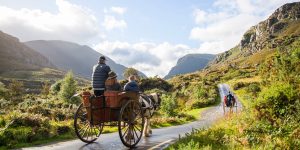 Horse and carriage with people on rural road with mountain views