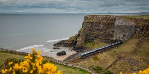 Train emerging from tunnel with beach and ocean alongside