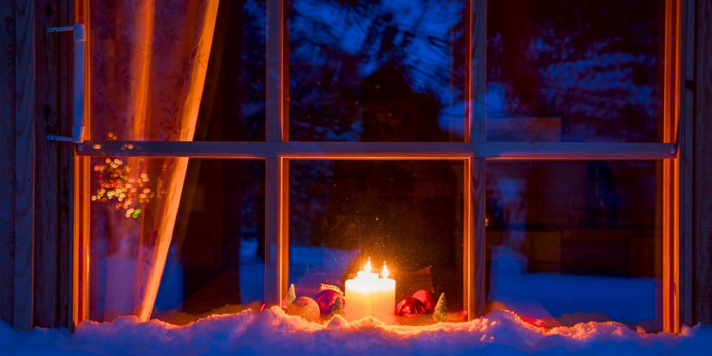 Candle and ornaments in window reflecting winter scene