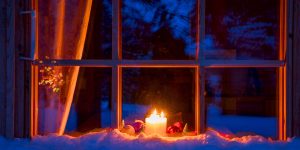 Candle and ornaments in window reflecting winter scene