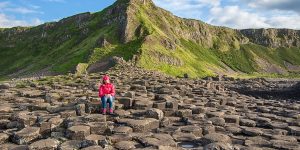 Person sitting on a basalt column at the Giants Causeway
