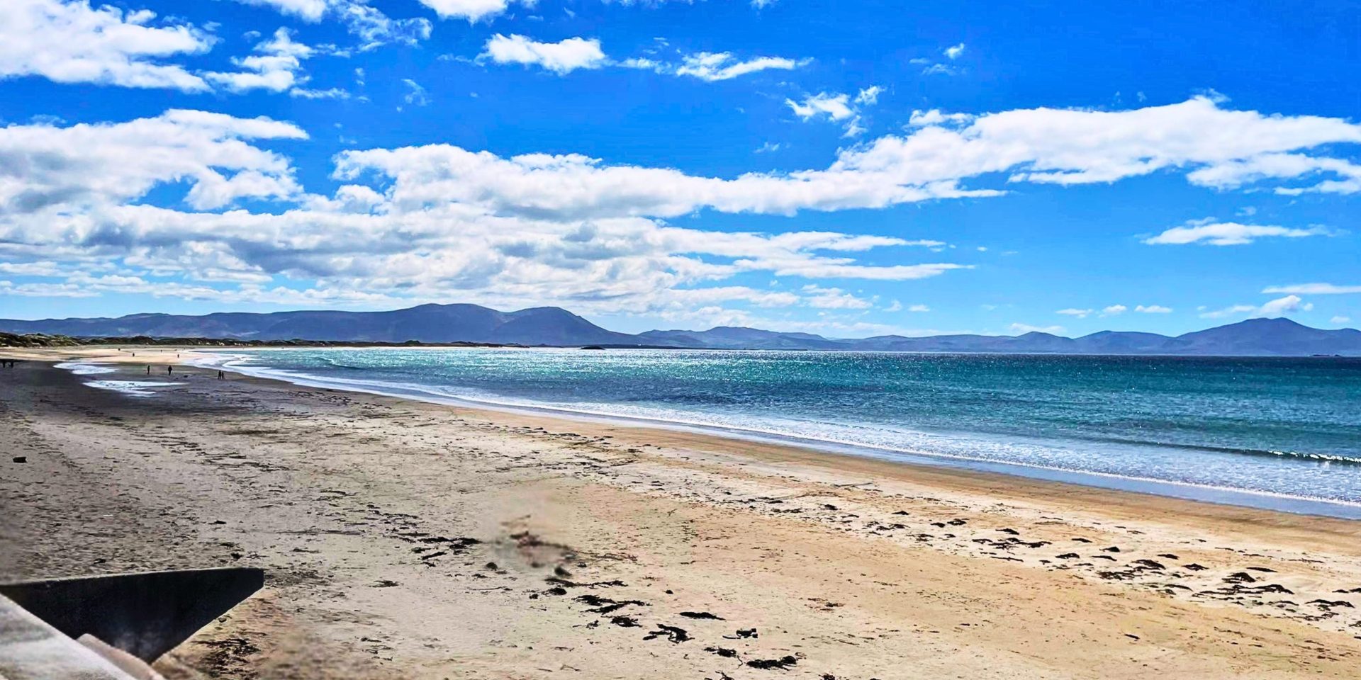 View of beach in Ireland with blue sky and mountains in the distance