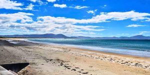 View of beach in Ireland with blue sky and mountains in the distance