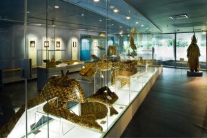 A long glass display case inside a museum exhibition hall containing various historic Irish artifacts.