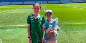 Two young girls smiling for a picture in a large empty stadium.