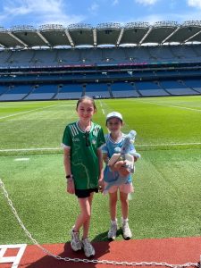 Two young girls posing for a picture in an empty large stadium.